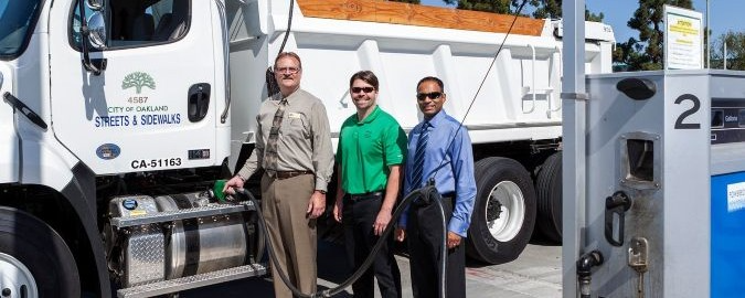 Three men stand in front of a heavy-duty diesel vehicle that they are fueling with renewable diesel. Text on the vehicle reads “City of Oakland Streets & Sidewalks.”